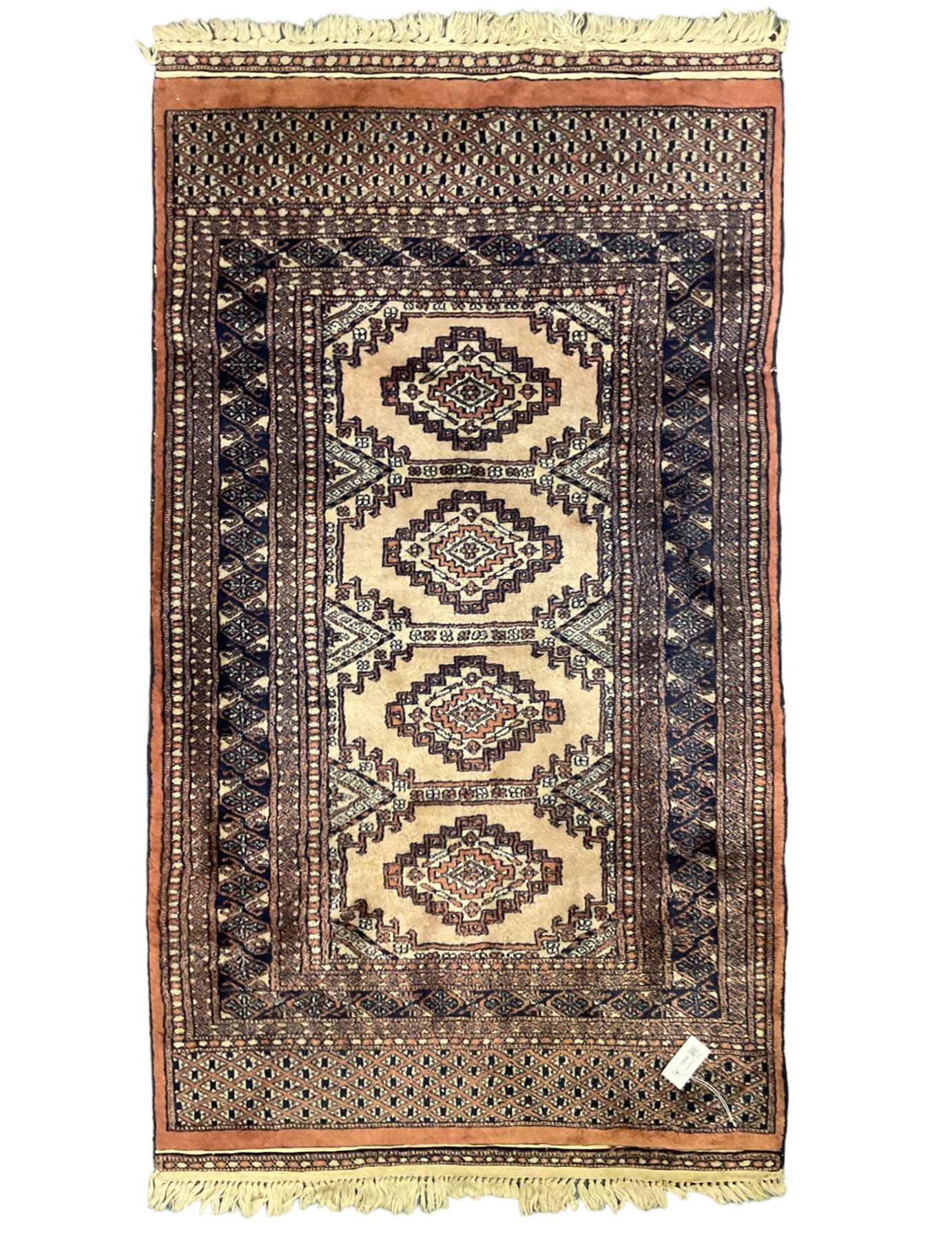 Persian peach ground rug, the field divided into four panels each with geometric lozenge, multiple band border with stylised flower head motifs, the end panels decorated with repeating lozenges