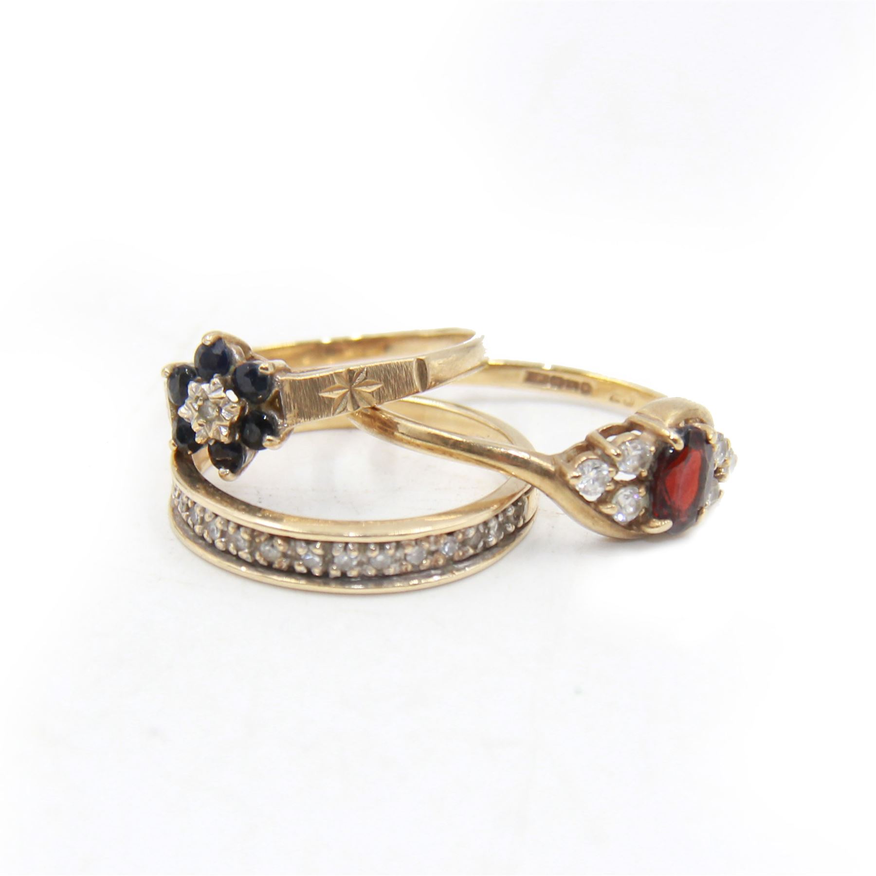 Three 9ct gold stone set rings, to include a sapphire and diamond flower head ring, eternity ring and one other, all stamped or hallmarked