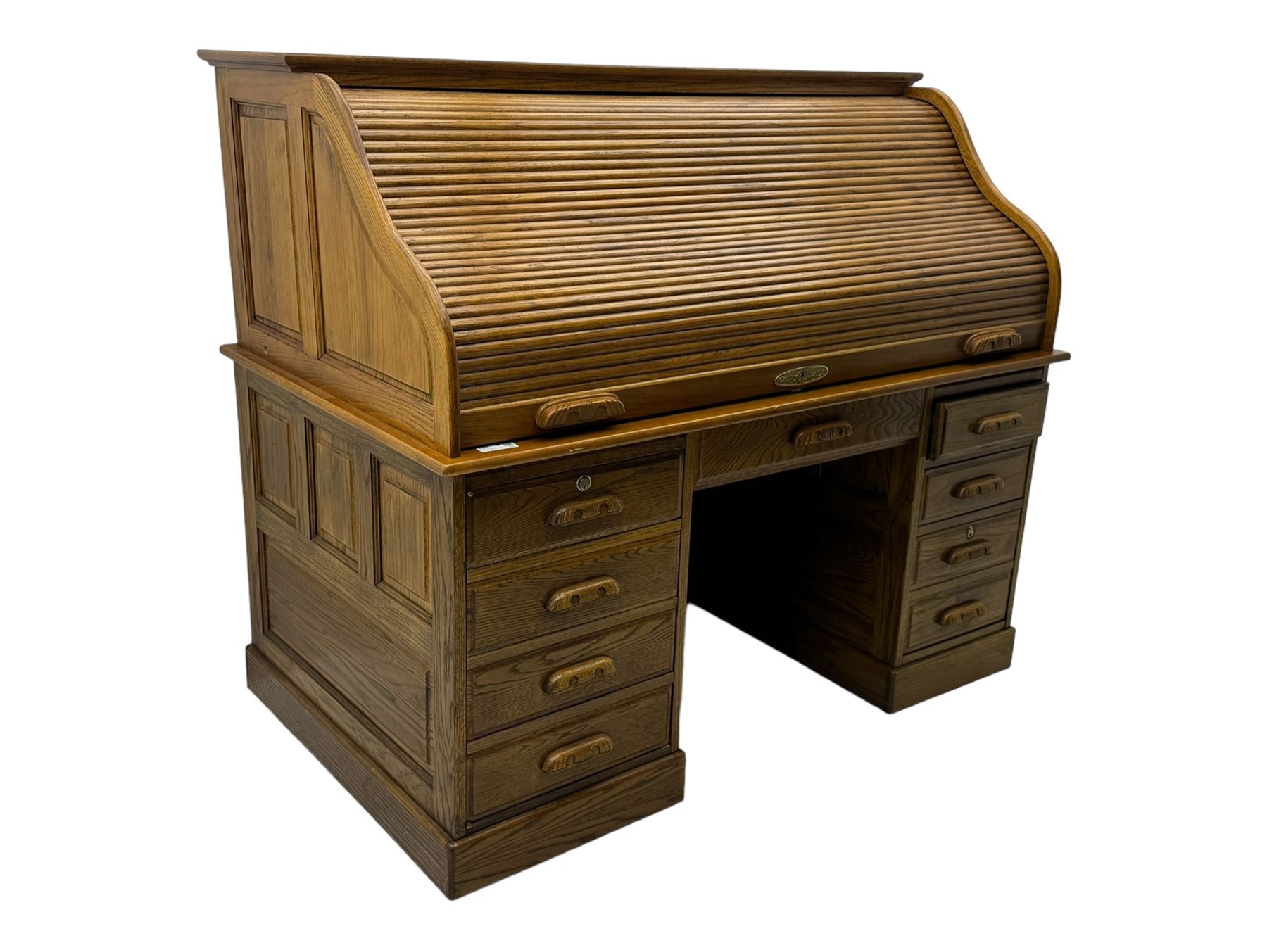 Early 20th century oak tambour roll-top desk, the top with fitted interior including drawers, pigeonholes and compartments, the twin pedestals fitted with four drawers with carved handles, supported by plinth base 