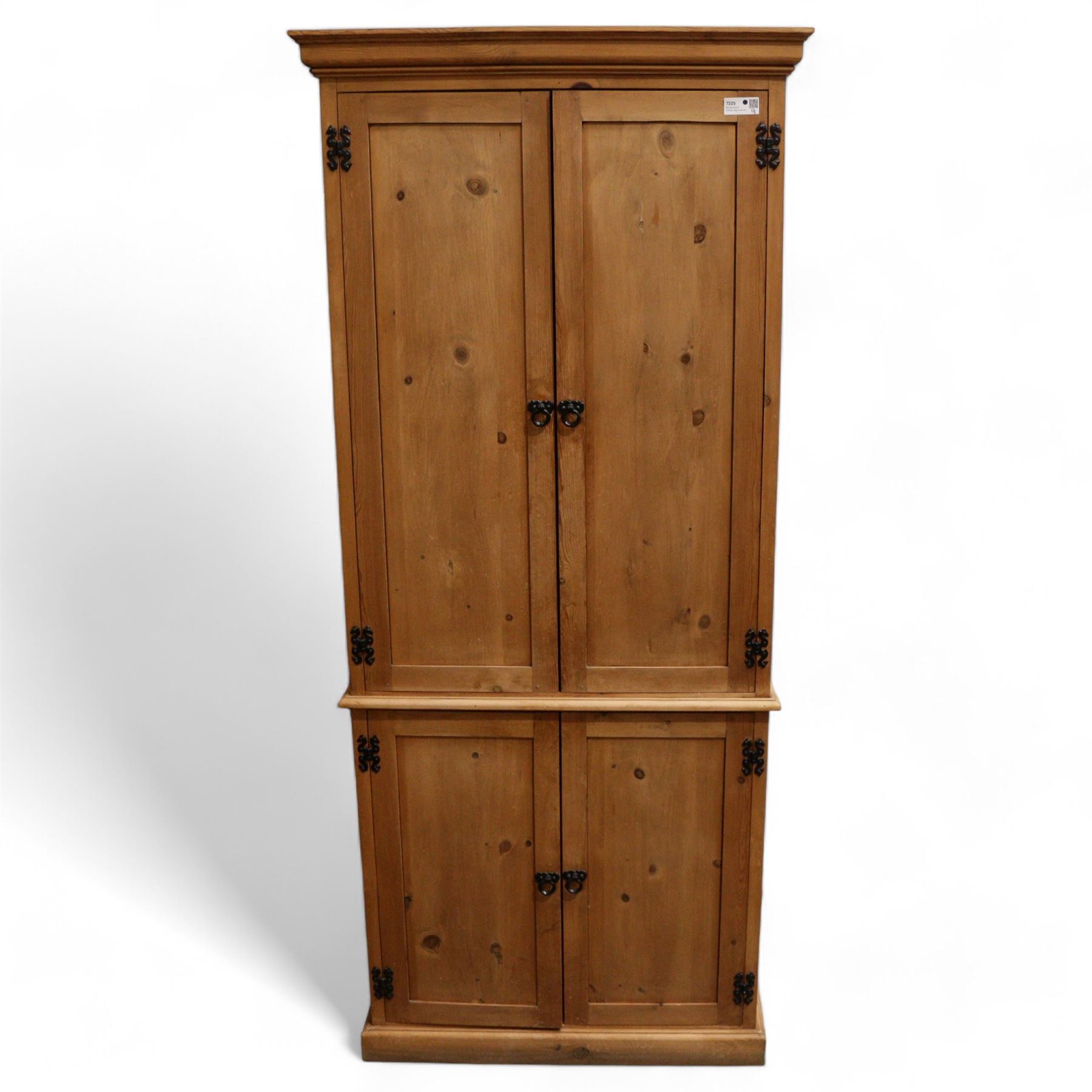 Tall 20th century stained pine cupboard, projecting cornice over four panelled cupboard doors, enclosing shelves, on skirted base, with iron fittings and handles