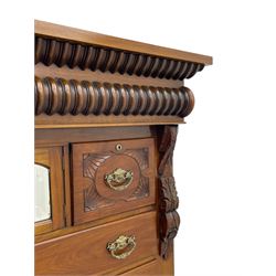 Late Victorian walnut Scotch chest, projecting cornice with turned quarter column mounts over matching half column to frieze, fitted with two upper short drawers with central cupboard, bevelled mirror glazed cupboard door, four graduating drawers below, foliage and flower head carved brackets to the uprights, panelled sides, chamfered plinth on turned feet