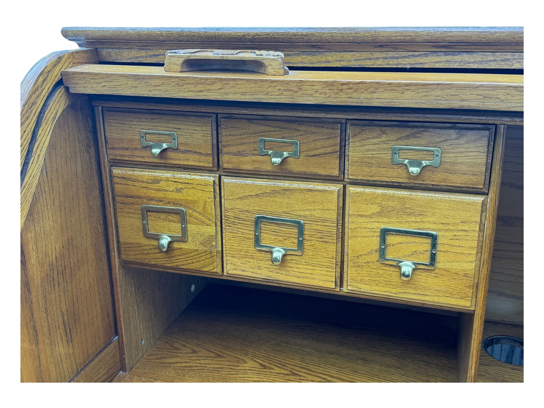 Early 20th century oak tambour roll-top desk, the top with fitted interior including drawers, pigeonholes and compartments, the twin pedestals fitted with four drawers with carved handles, supported by plinth base 