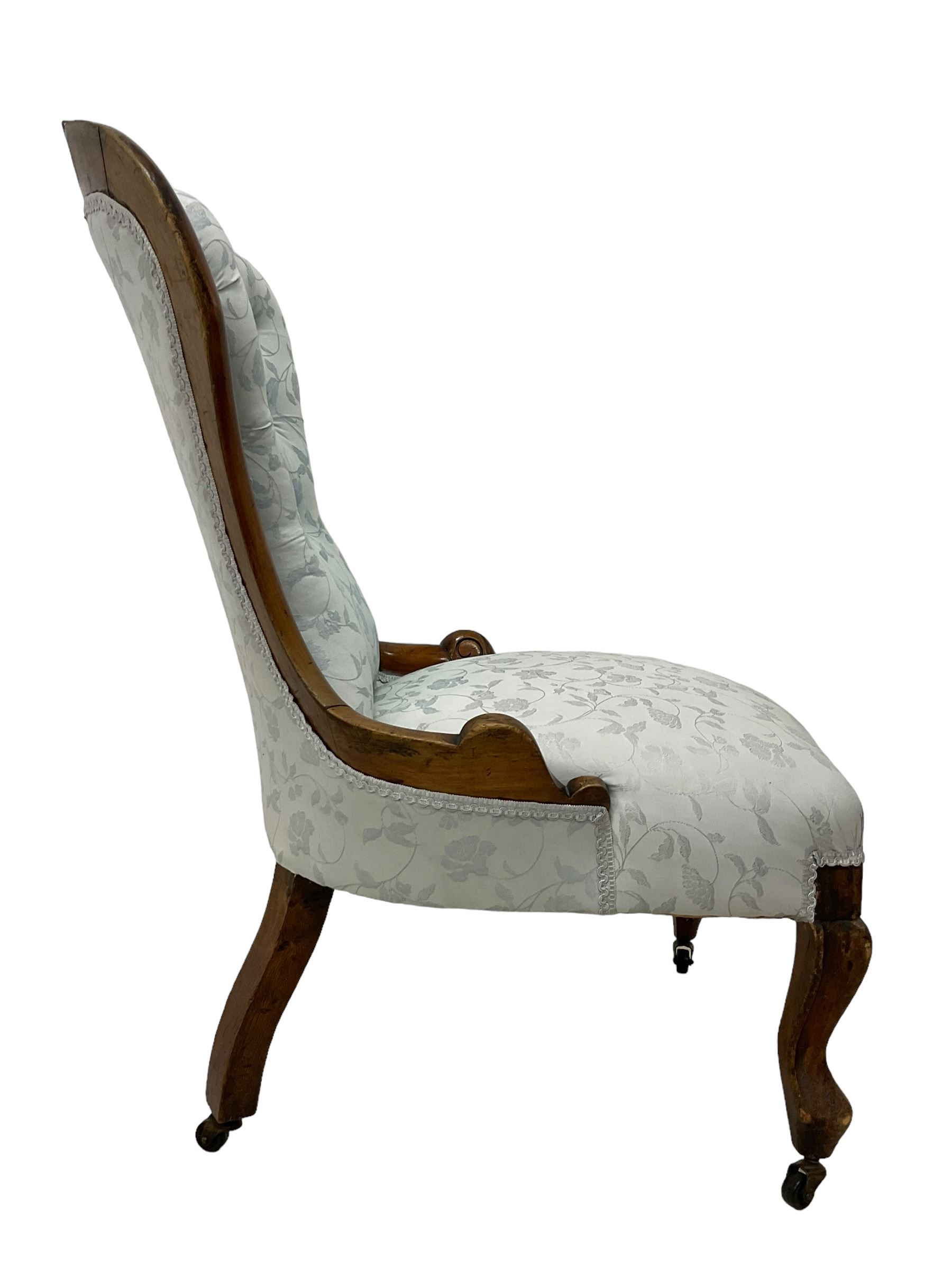 Victorian walnut nursing chair, the curved cresting rail carved with central cartouche and scroll leaves, upholstered in pale blue fabric decorated with trailing floral design, on cabriole front feet 