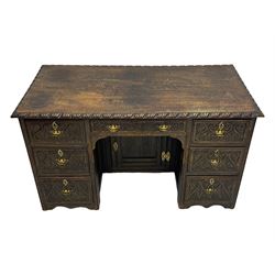 Victorian carved oak kneehole desk, the rectangular top with carved edge, above central drawer with carved front and brass handles, central kneehole with cupboard door, flanked by two banks of three graduating drawers each with similarly carved decoration, on shaped plinth base with castors