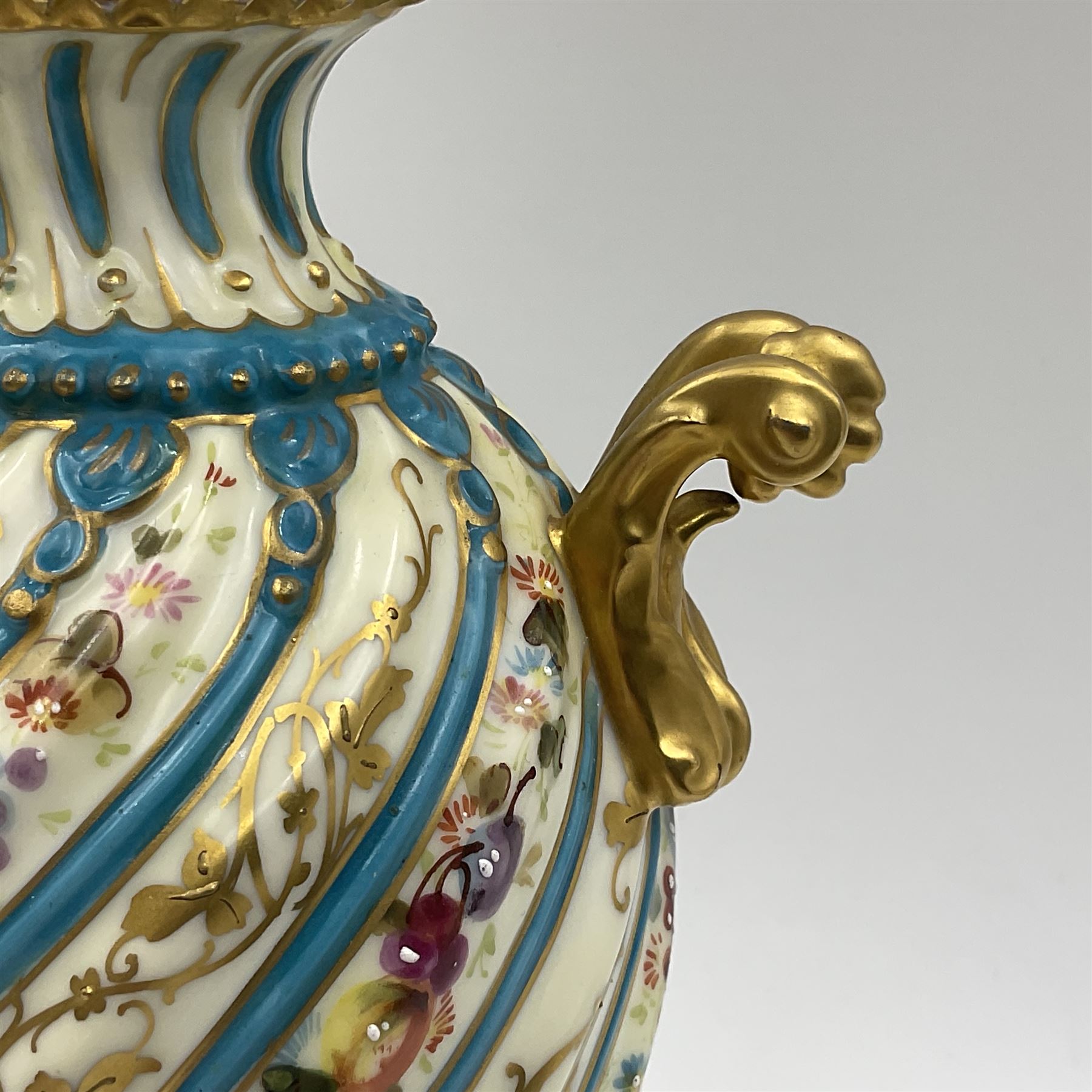 Pair of late 19th/early 20th century Sevres style vases and covers, of baluster form with gilt scroll handles and domed covers, the wrythen fluted bodies decorated with alternating bands of painted fruit and flowers and gilt vines, upon a white and celeste blue ground, with printed and impressed marks beneath, H22.5cm 