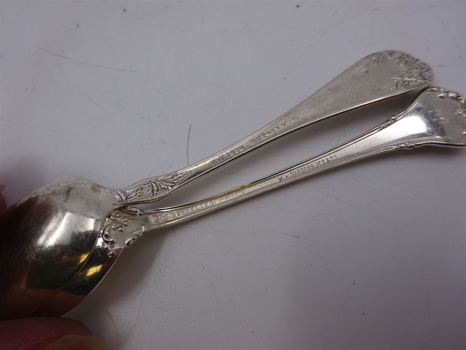 Two sets of twelve late 19th/ early 20th century American silver coffee spoons, the first set with engraved initial to terminal within scrolling border and engraved date verso, the second set with embossed floral decoration to handles, all stamped Sterling 