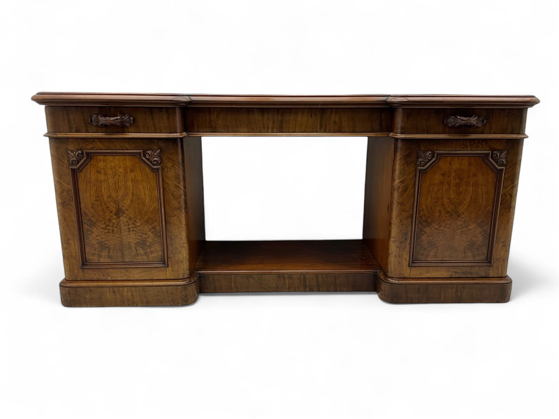 Mid-19th century figured mahogany sideboard, moulded reverse-break front, fitted with three drawers and two cupboards, carved faux bois handles, enclosed by panelled doors with book-matched veneers, applied geometric mouldings and scroll leaf decoration, on moulded plinth base 