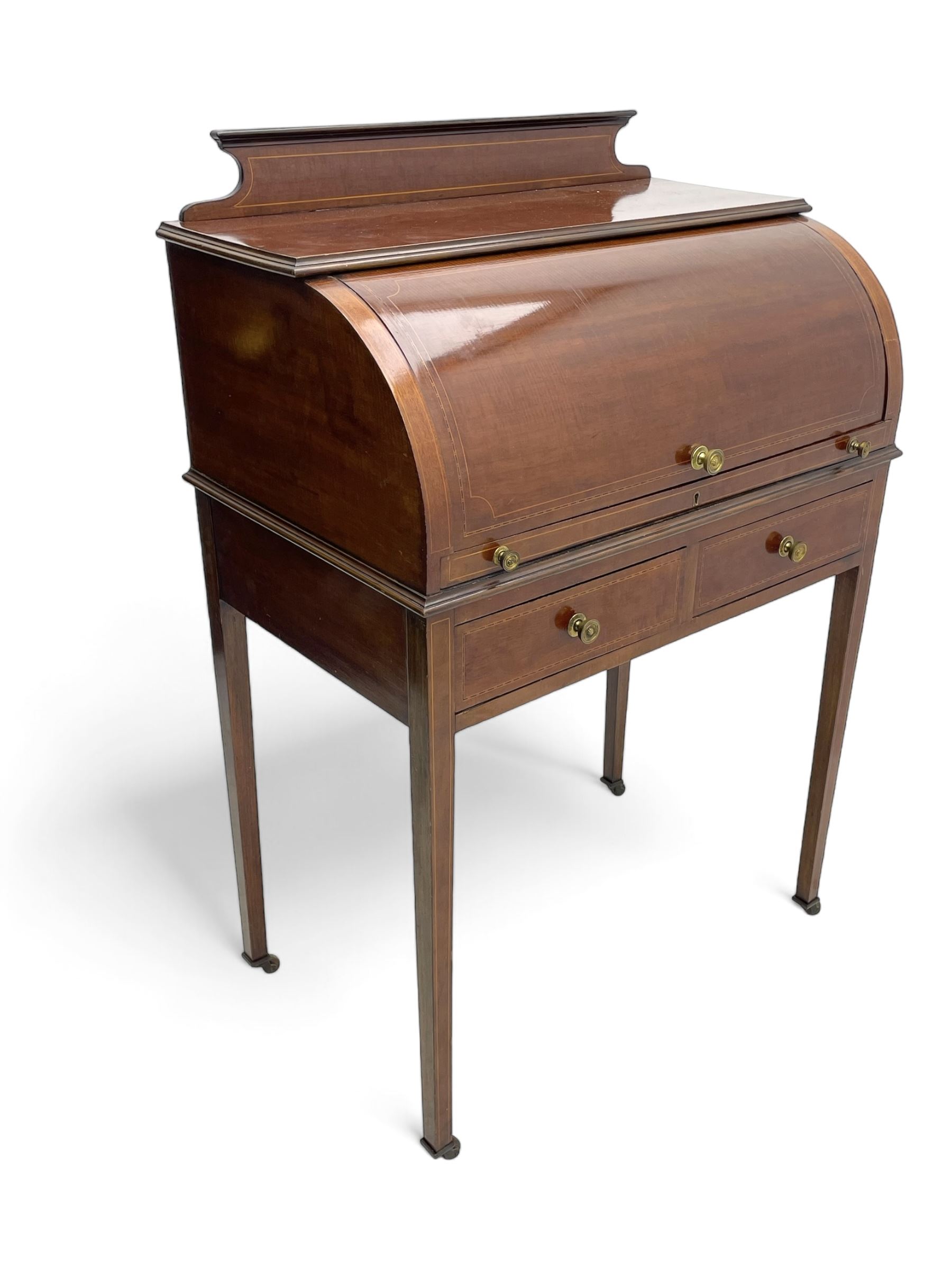 Edwardian inlaid mahogany roll-top desk, cylindrical lid enclosing fitted interior with pigeonholes, drawers and retractable writing surface, over two drawers with brass pull handles, on tapered supports with brass and ceramic castors