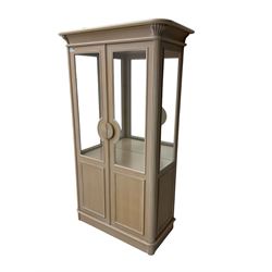 Contemporary display cabinet, moulded cornice above glazed panelled doors with central carved sunburst handles, mirrored back interior with lighting, lower enclosed storage compartment, raised on plinth base