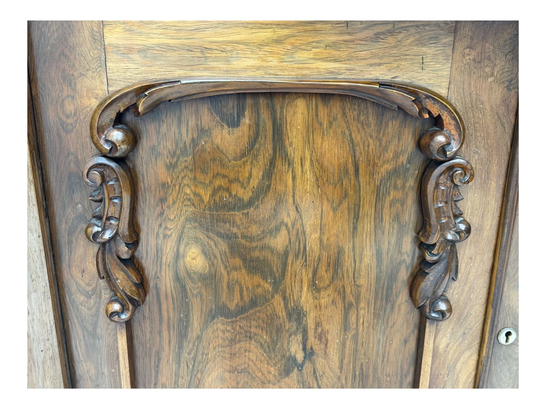 Mid-19th century rosewood chiffonier, raised back with scroll and leaf carved shaped pediment, serpentine top over drawer and double cupboard with scrollwork decoration, on shaped plinth base