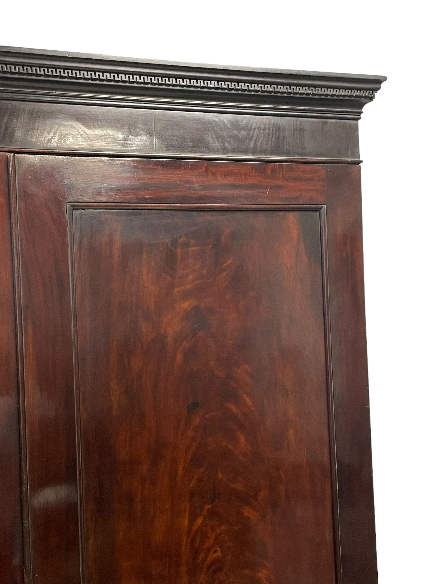 19th century Irish mahogany press wardrobe, projecting dentil cornice over two figured panelled doors, enclosing three sliding trays and hanging rail with coat hooks, fitted with two drawers to base over a shaped apron, raised on acanthus carved cabriole supports with paw feet, retailed by Millar & Beatty of Dublin, with paper labels verso, collected and restored by Michael Butler (1870-1900), impressed stamp to side and ink stamp to drawer inscribed 'M Butler collector of high-class furniture and works of art'