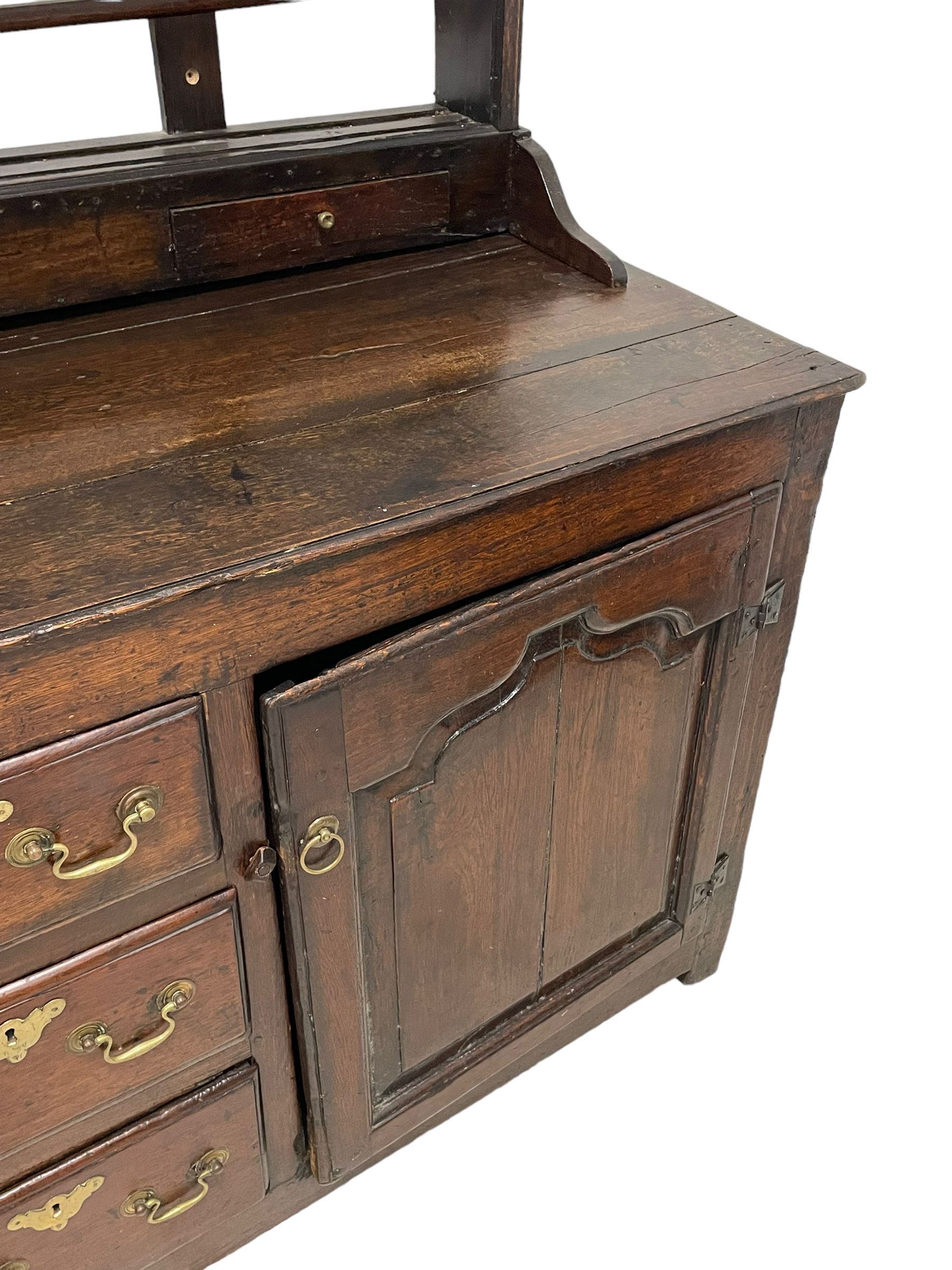 18th century oak dresser, projecting cornice over three heights plate rack with three small drawers, rectangular ovolo-moulded top over three central drawers and two flanking cupboards, enclosed by fielded panelled doors, on stile supports 