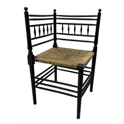 In the manner of William Morris - Arts & Crafts period corner chair, swell turned horizontal rails with balustrade back, rush seat on ring turned supports, black paint finish 