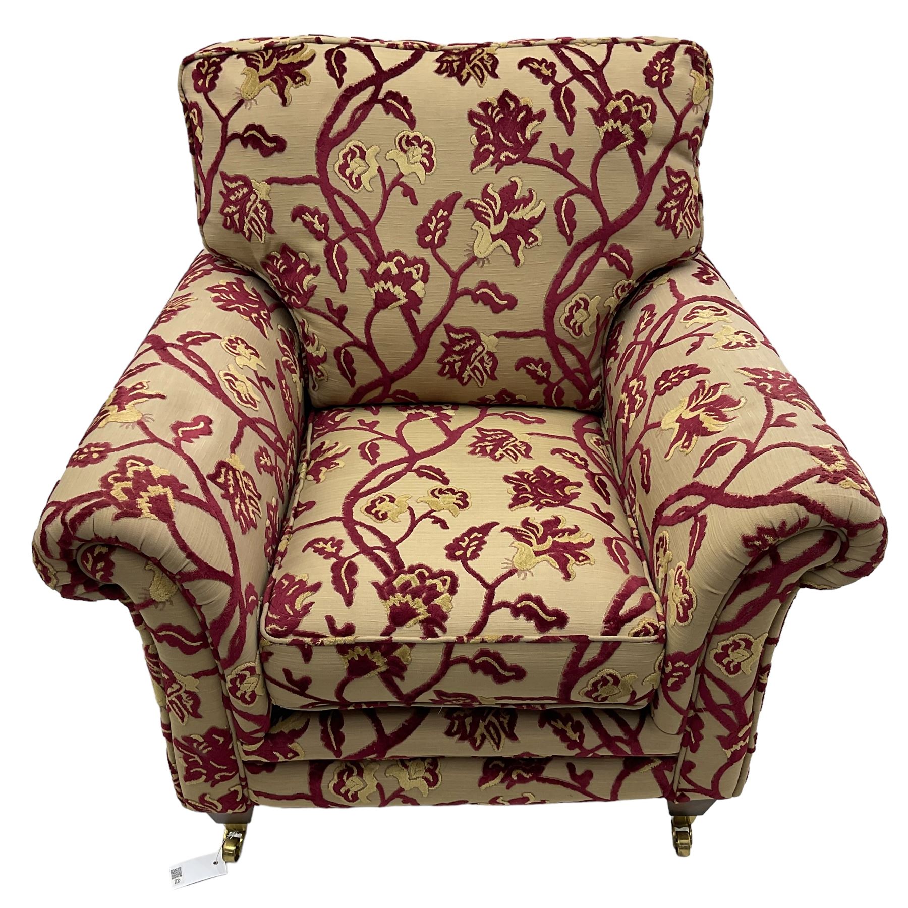 Contemporary upholstered armchair, scroll arms and loose cushions, embossed beige ground fabric with red and gold floral motifs, on tapered wooden supports with front brass castors