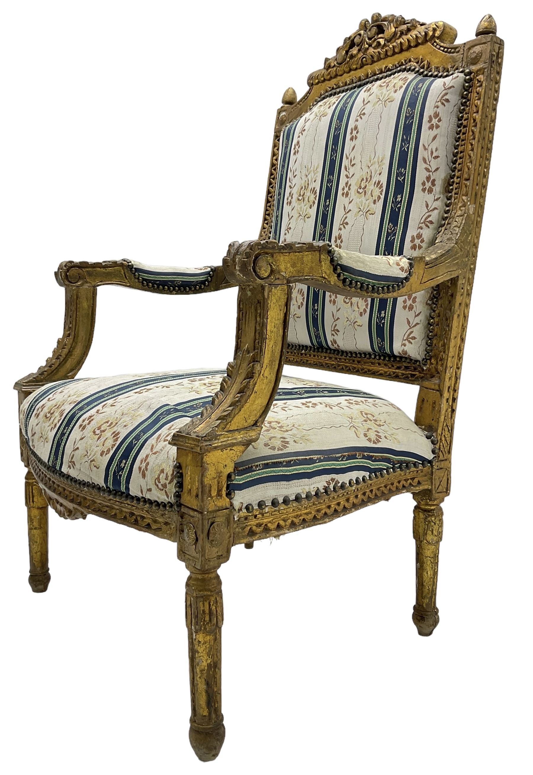 Late 20th century French design carved giltwood armchair, the cresting rail carved with scrolled foliage over foliate carved platform, upholstered in striped fabric decorated with trailing foliage and flower heads, acanthus carved arm terminals and upright supports, on turned and fluted supports 