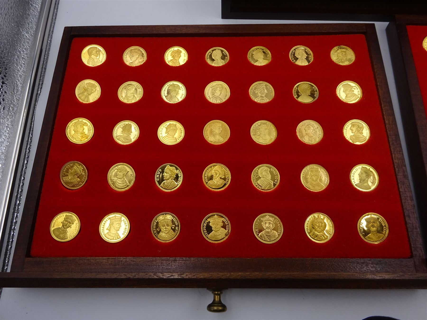 Danbury Mint, Our Royal Sovereigns Collection, seventy 22 carat gold plated silver medallions depicting the complete line of British monarchs to mark the 1200th anniversary of the first coronation, contained within wooden table top collectors cabinet with two drawers, with certificate of authenticity, with two drawers, hallmarked Danbury Mint, London various dates