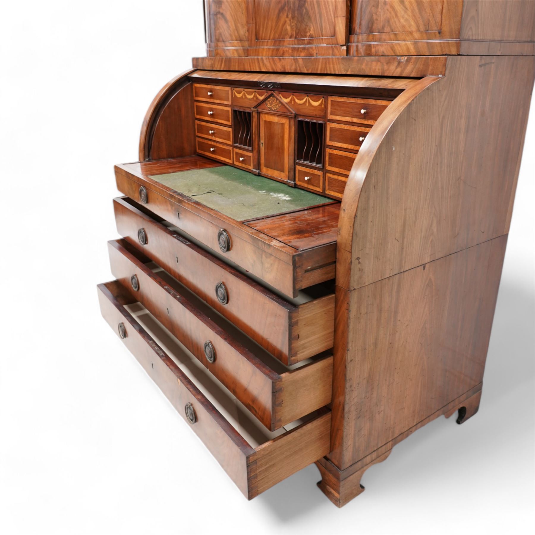 19th century Biedermeier figured mahogany cylinder bureau cabinet, the raised super structure with stepped pointed pediment over hidden cupboard and hinged fall front, the interior fitted with pigeonholes and secret drawers behind rusticated inlay, curved flanking cupboards fitted with internal drawers, the cylinder top opens to reveal small drawers, document divisions and secret compartments, sliding desk with central hinged writing surface, inlaid with satinwood bands and draped festoons, fitted with three long drawers, on bracket feet