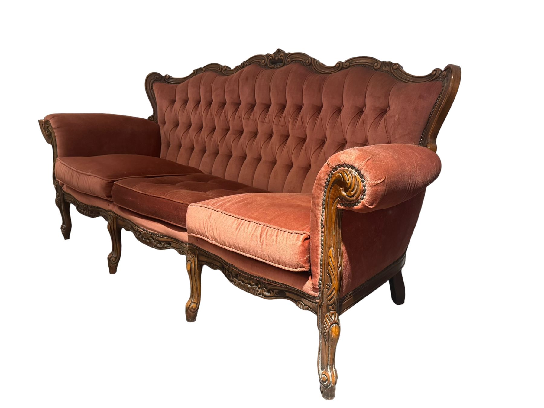 Late 20th century French walnut framed three-seat sofa, high shaped back with floral carved cresting rail, deep-buttoned coral velvet upholstery with loose seat cushions, scrolling arm terminals over moulded walnut frame, raised on cabriole supports