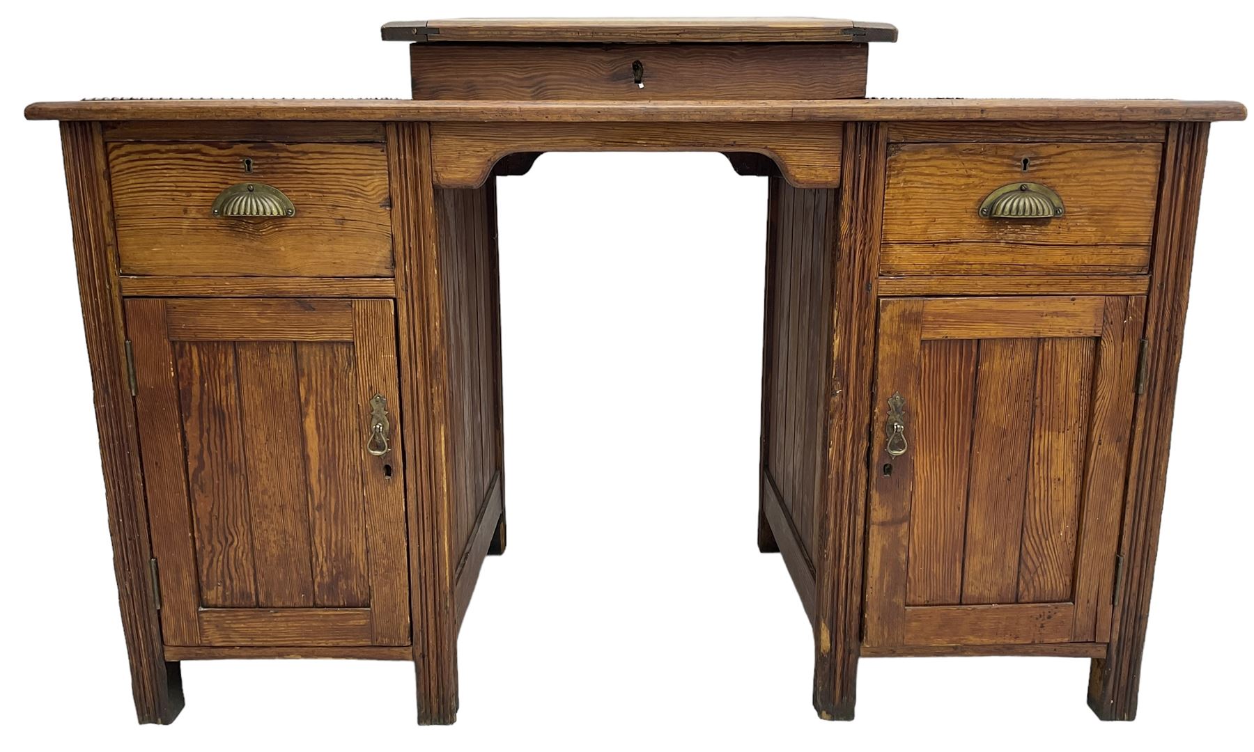 Edwardian pitch pine desk, rectangular top with writing slope flanked by inset leather writing surfaces, over twin pedestals each with shell cup handled drawer over cupboard, the left enclosing two shelves, the right enclosing sliding trays, on fluted straight supports