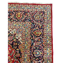 Persian Kashan crimson ground carpet, floral design central medallion surrounded by trailing leafy branches and stylised plant motifs, multi-band border with repeating floral design