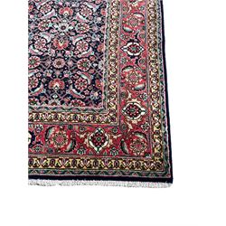 Persian Farahan indigo ground rug, the field decorated with large repeating floral herati motifs, crimson ground border decorated with palmettes and trailing leafy branch, within guard stripes 