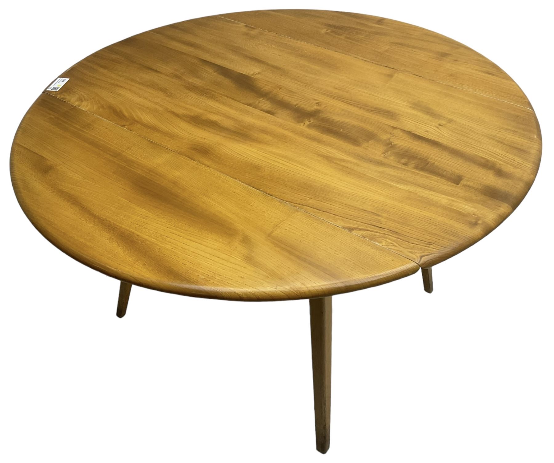 Ercol - mid-20th century golden elm drop-leaf dining table, circular top over splayed supports