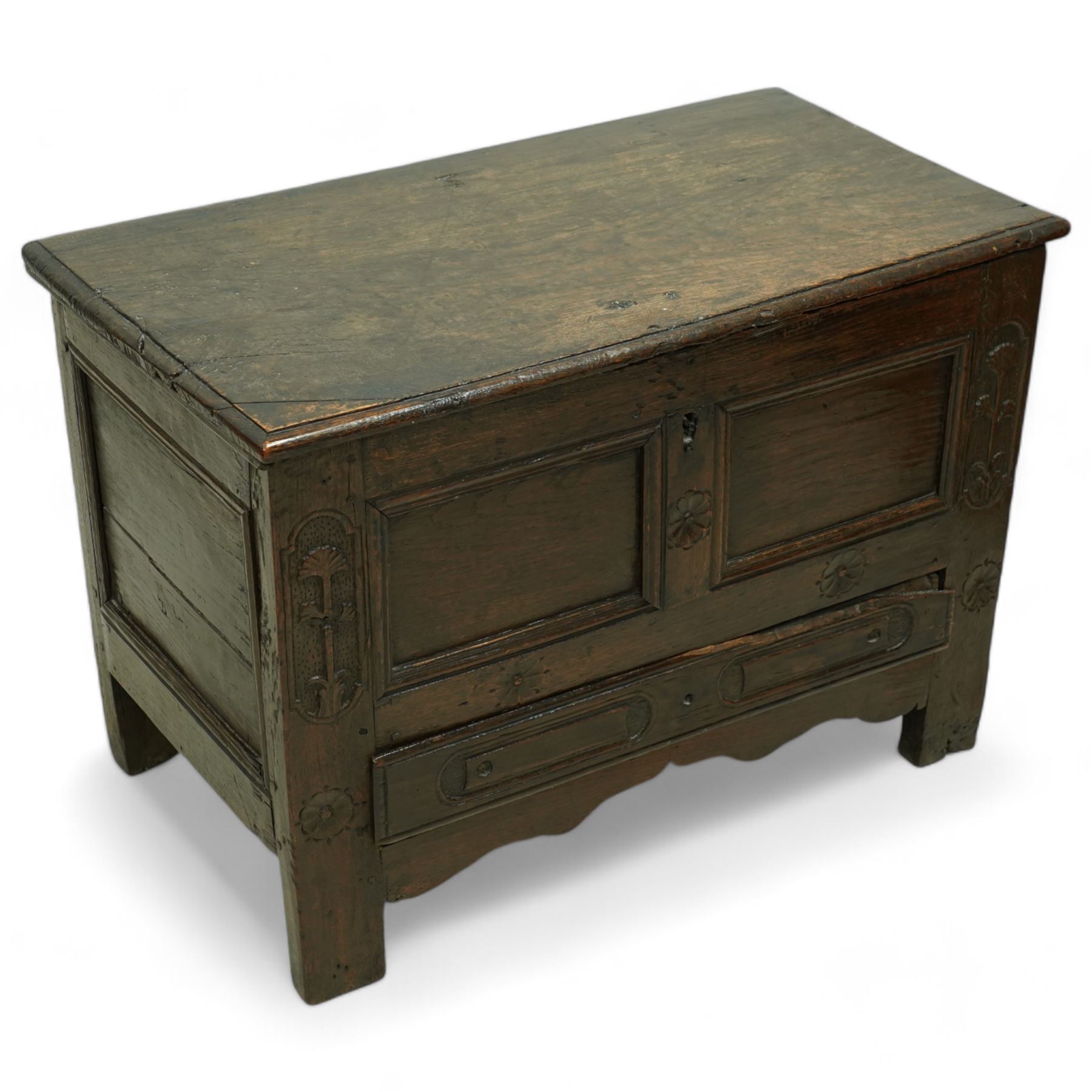 Small 18th century oak mule chest, rectangular hinged top top with moulded edge, enclosing candle box, over a double panelled front flanked by foliate carvings, single drawer fitted to base, on stile supports