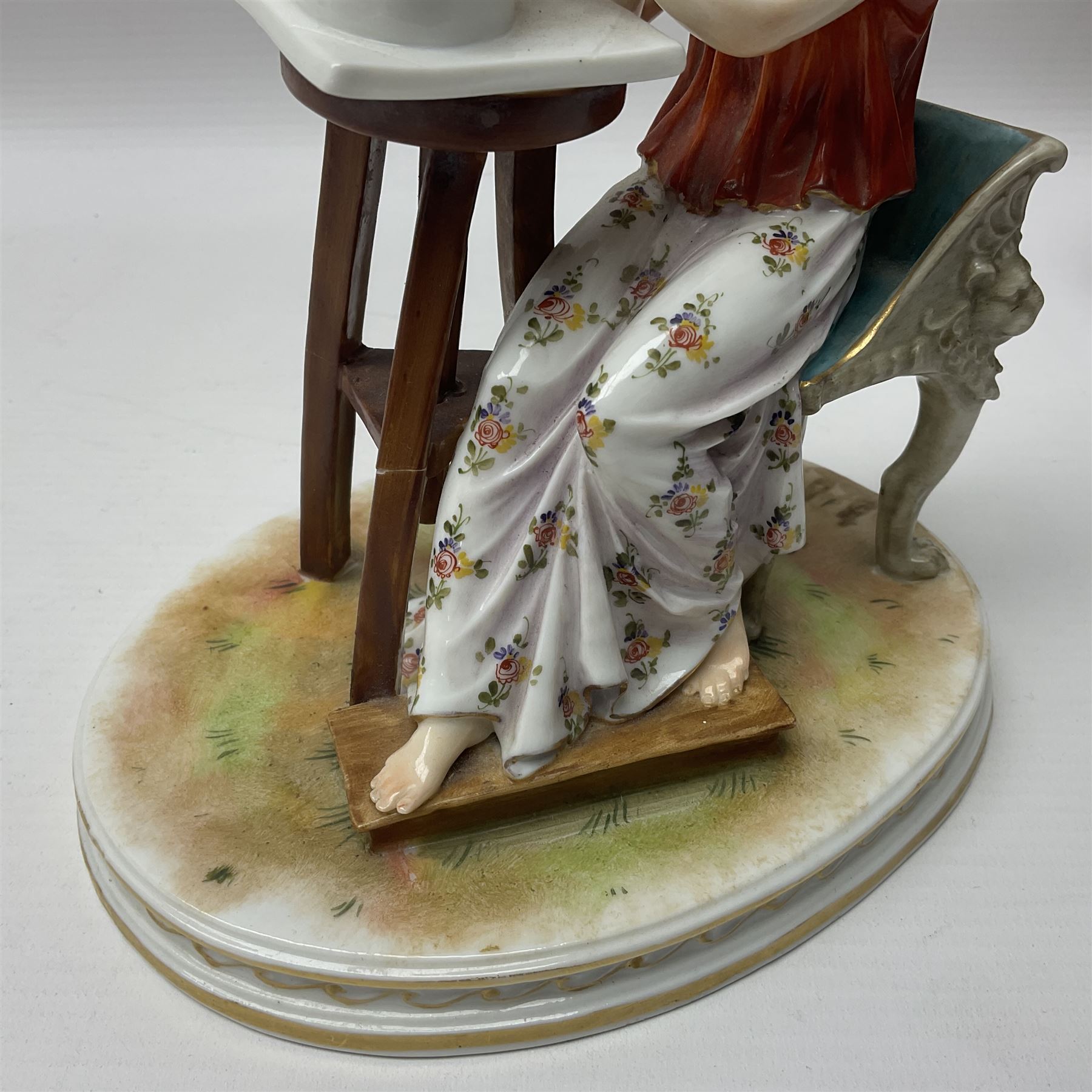 Pair of late 19th/early 20th century Naples figures modelled engaged in the arts, the first example modelled as a female figure seated before an easel, painting a figural scene, the second modelled as a female figure seated before a bust with scultping tools in hand, each upon an oval base with naturalistic painted ground, each with blue crowned N mark beneath, each approximately H16cm, including base L15xm
