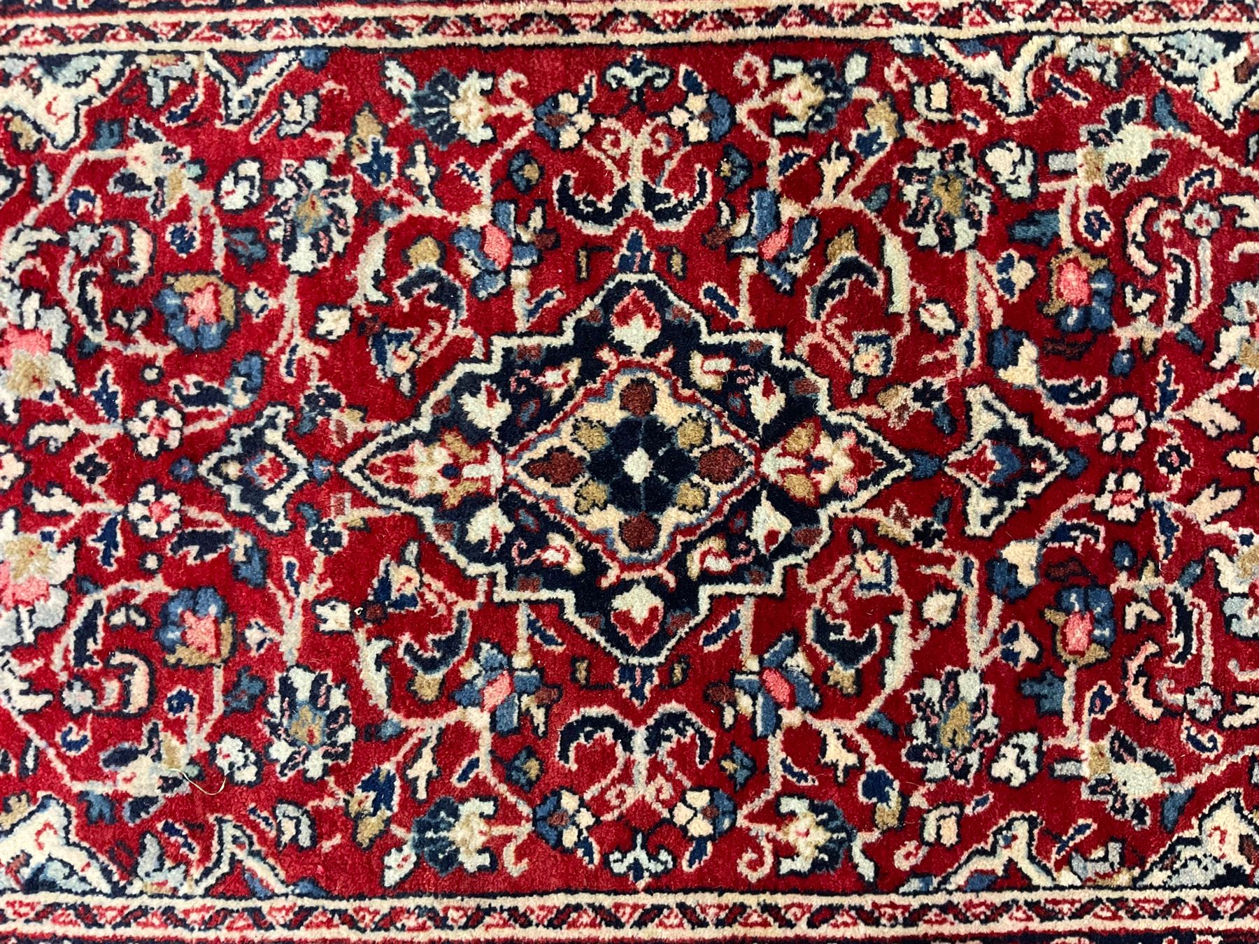 Persian crimson ground rug or mat, field decorated with central medallion and all-over scrolling floral motifs, border with repeating palmettes