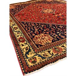 South West Persian Abadeh crimson ground rug, indigo ground with crimson lozenge field, decorated all over with small stylised motifs of flowerheads, hooks, animals and birds, guarded border decorated with trailing leaves and stylised plant motifs 