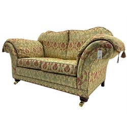 Traditional design two seat sofa, high back with scrolled arms, upholstered in beige fabric with red and green damask motifs, on castor supports (L178cm, D100cm, H89cm); matching armchair (L109cm, D89cm, H89cm)