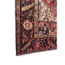 Persian Heriz red ground carpet, large central eight point medallion with projecting palmettes surrounded by small geometric motifs, decorated profusely with hooks, rosettes and animals, the busy border decorated with stylised foliate motifs within guard stripes 