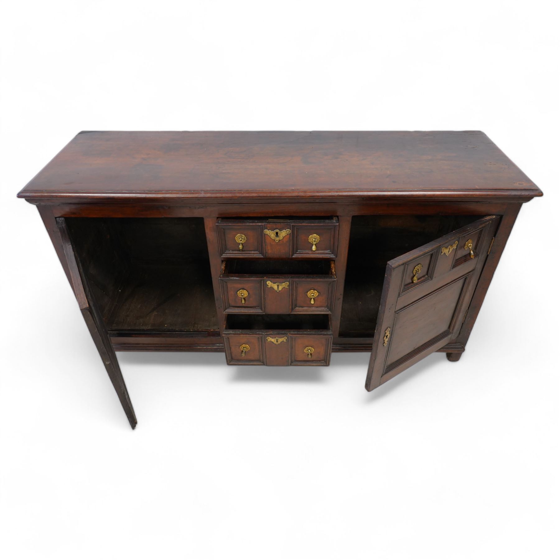 George III elm dresser base, the rectangular top with moulded edge, fitted with three central graduating twin-panelled drawers, flanked by two cupboard doors moulded with false drawer facias over large panels, lower moulded edge over stile feet