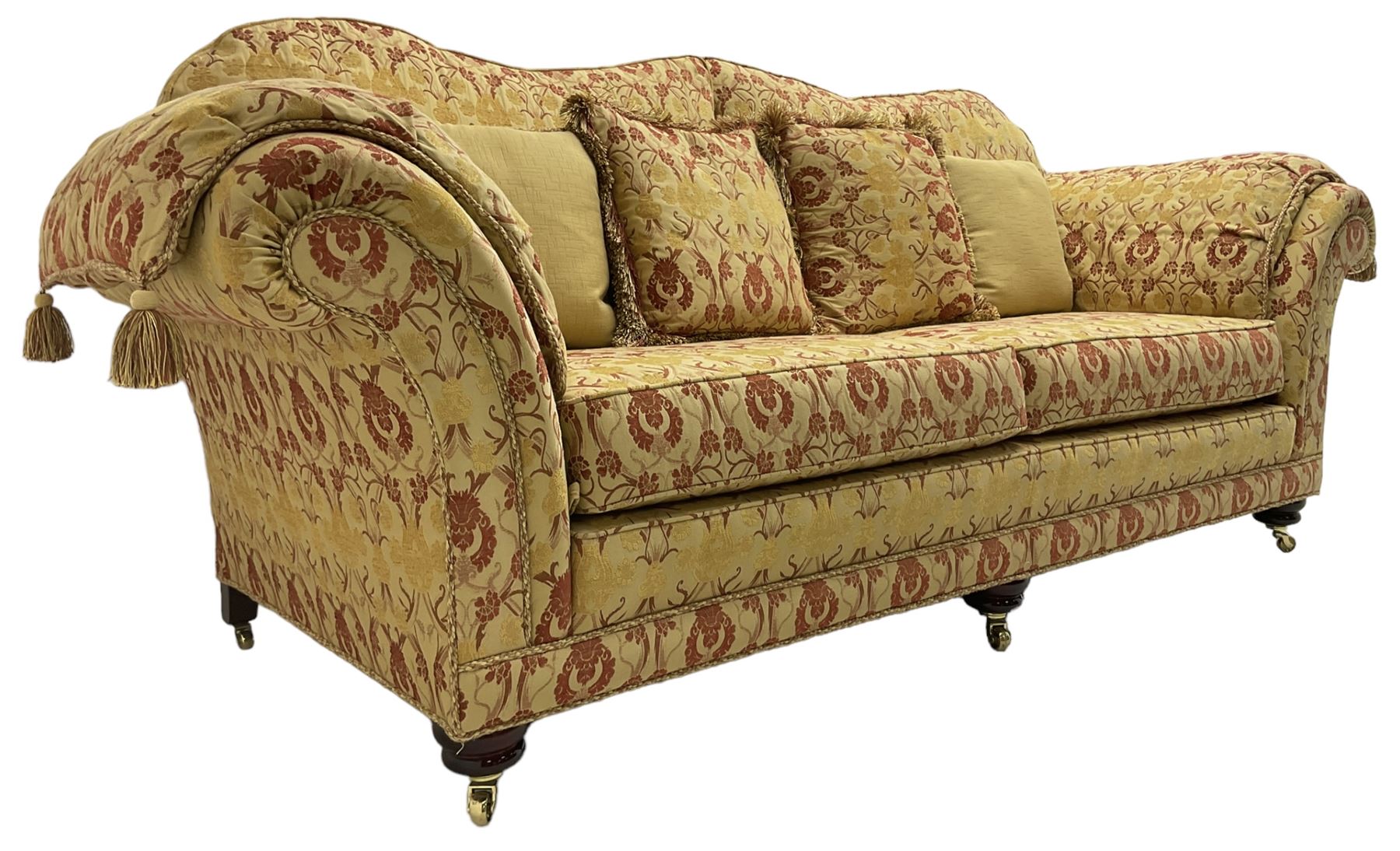 Steed Upholstery Ltd. - 'Lincoln' three-seat sofa upholstered in gold 'Olympia' floral pattern corded and tasselled fabric, together with scatter cushions and arm covers, on turned feet with brass castors