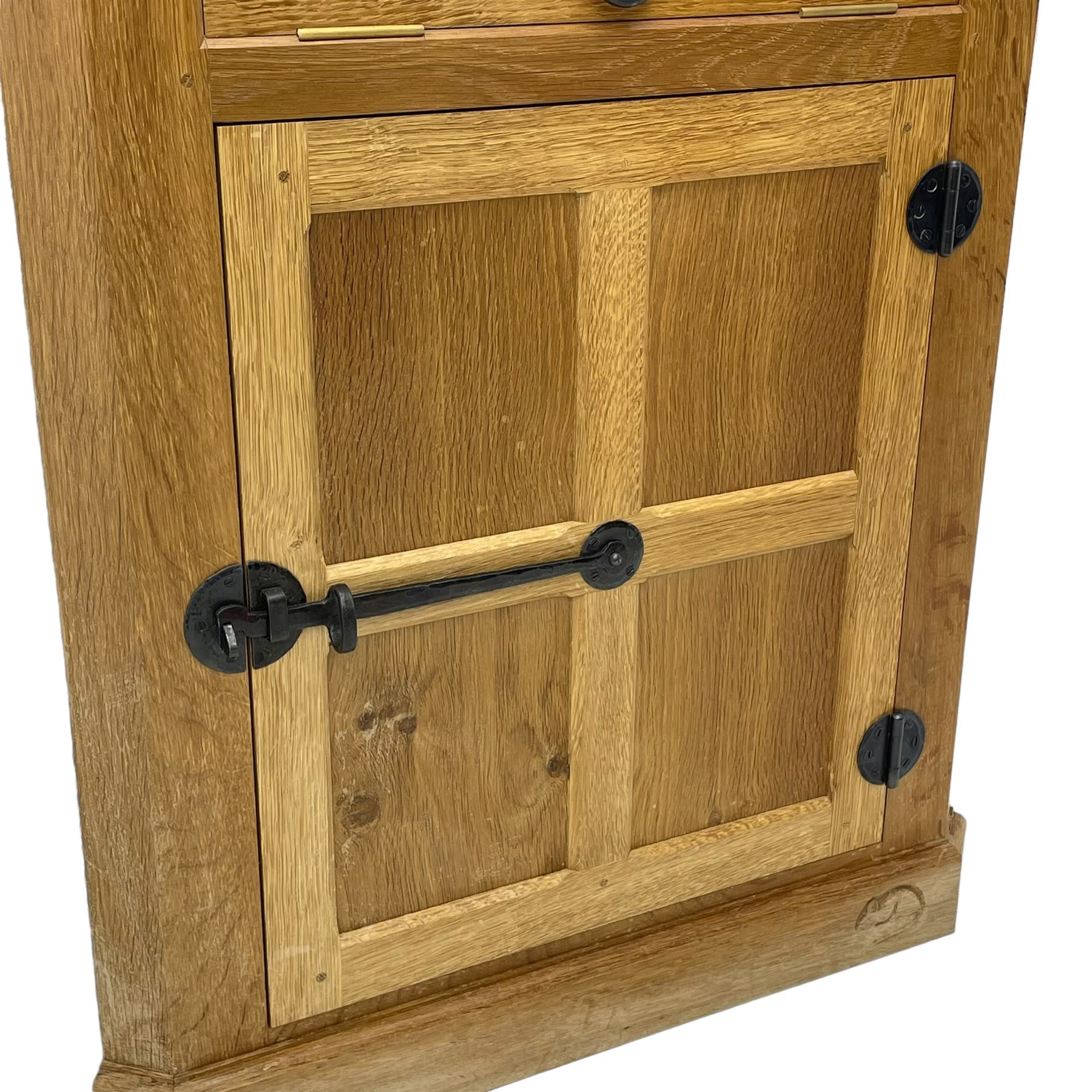 Mouseman - oak floor standing corner cupboard, fall front compartment over single panelled door, with wrought metal loop handle and latch, on moulded plinth base, carved in relief with mouse signature, by the workshop of Robert Thompson, Kilburn 