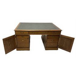 Late 19th century twin pedestal oak partner's desk, rectangular top with inset green leather writing surface, fitted with nine graduating drawers to each side, the rear drawers enclosed by panelled cupboards