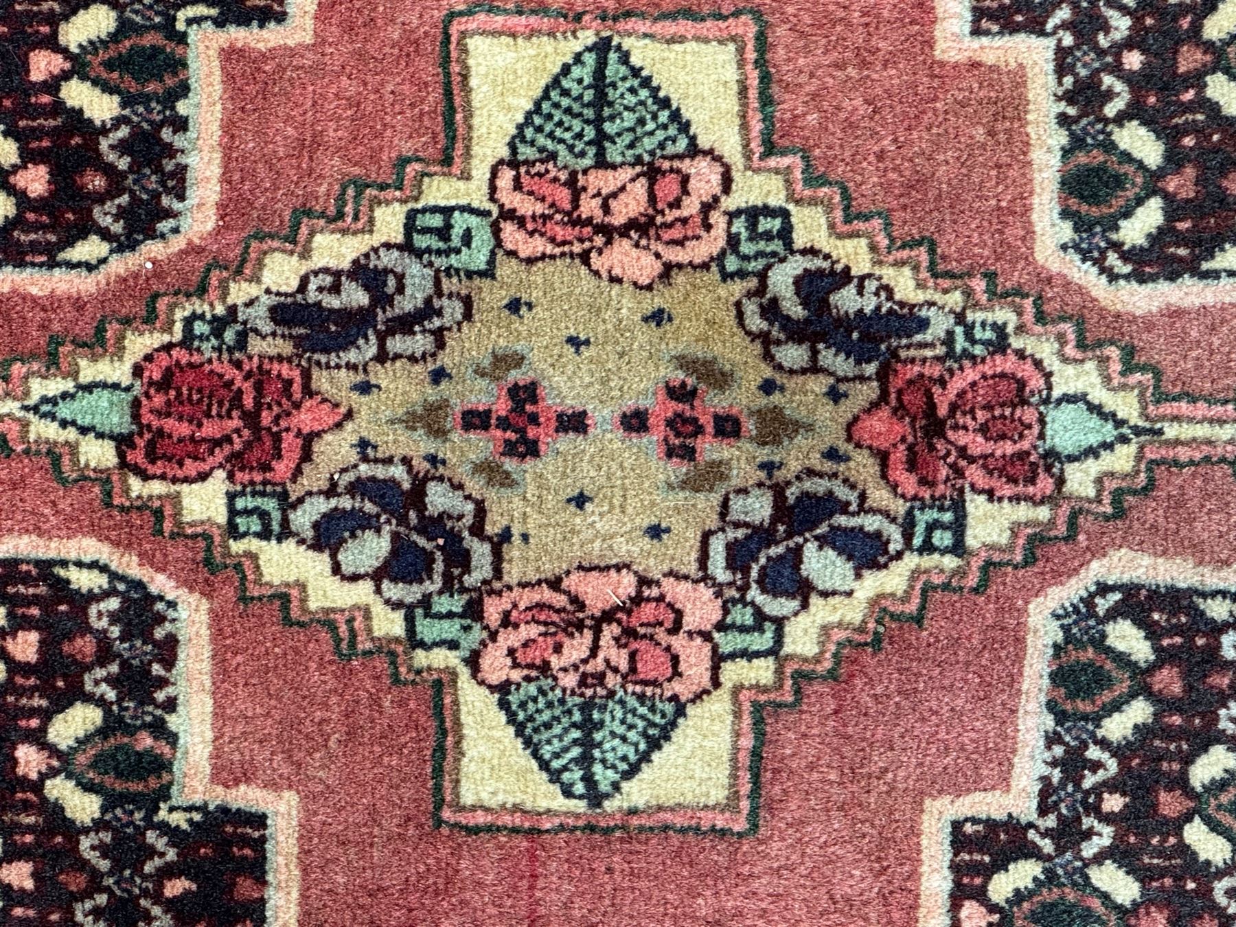 Kurdish rose ground runner rug, set with a series of ten floral medallions on linked field, the border decorated with stylised flower heads and bird motifs 