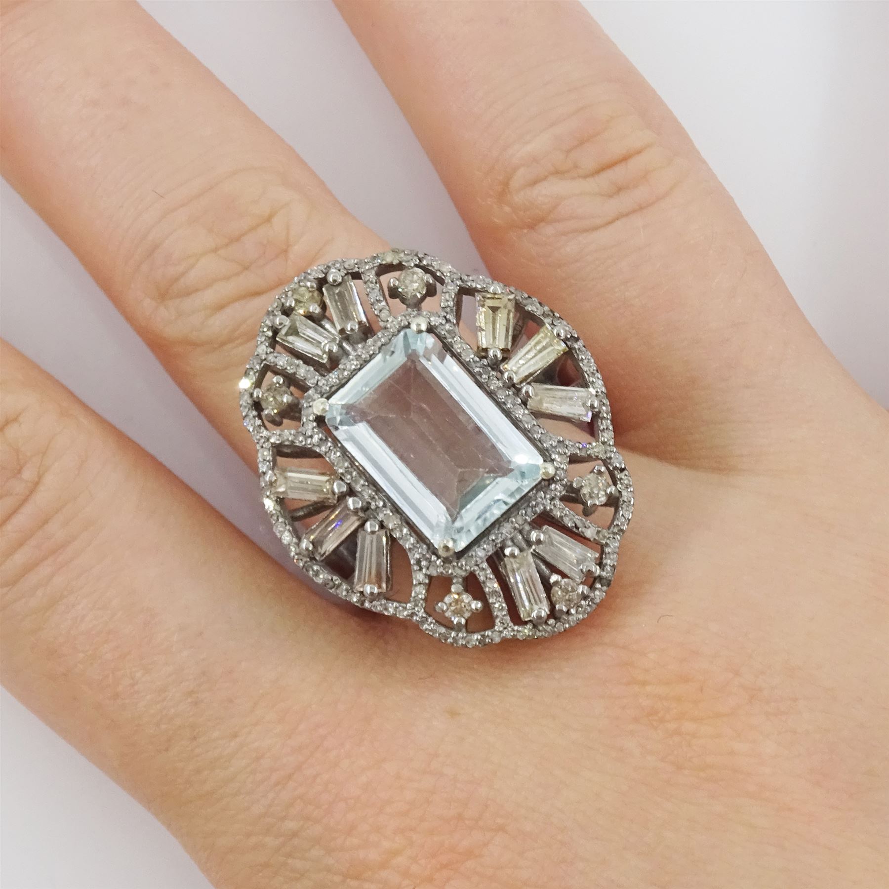 Large silver aquamarine and diamond pierced design ring, the central emerald cut aquamarine of approx 3.75 carat, with baguette and round brilliant cut diamond surround, total diamond weight approx 1.75 carat