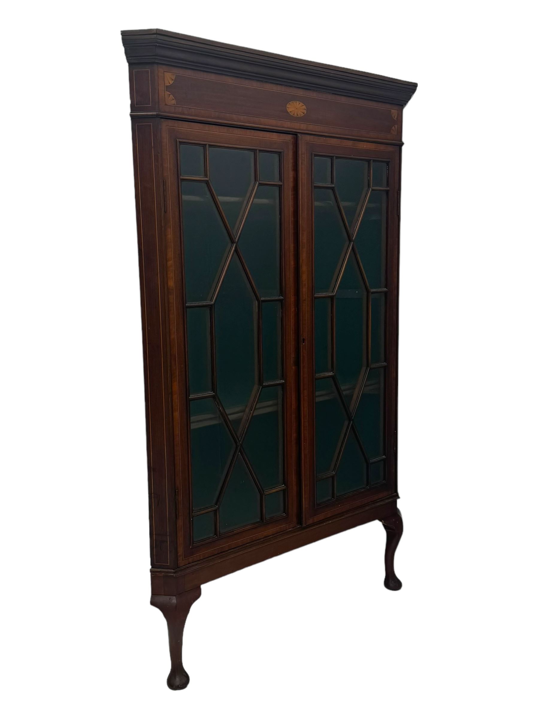 Edwardian mahogany corner cabinet, projecting cornice over inlaid frieze, two astragal glazed doors enclosing shelved interior, on cabriole supports