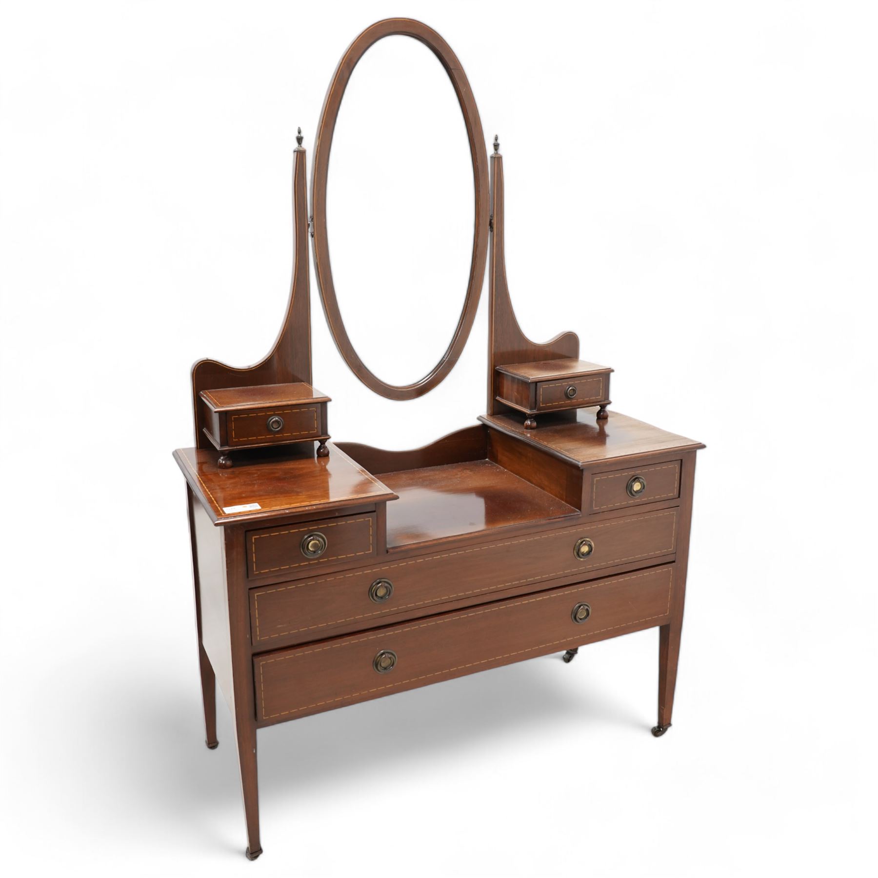 Edwardian inlaid mahogany drop-centre dressing table, bevelled oval swing mirror over trinket drawers, fitted with two short and two long drawers, on square tapering supports with brass castors