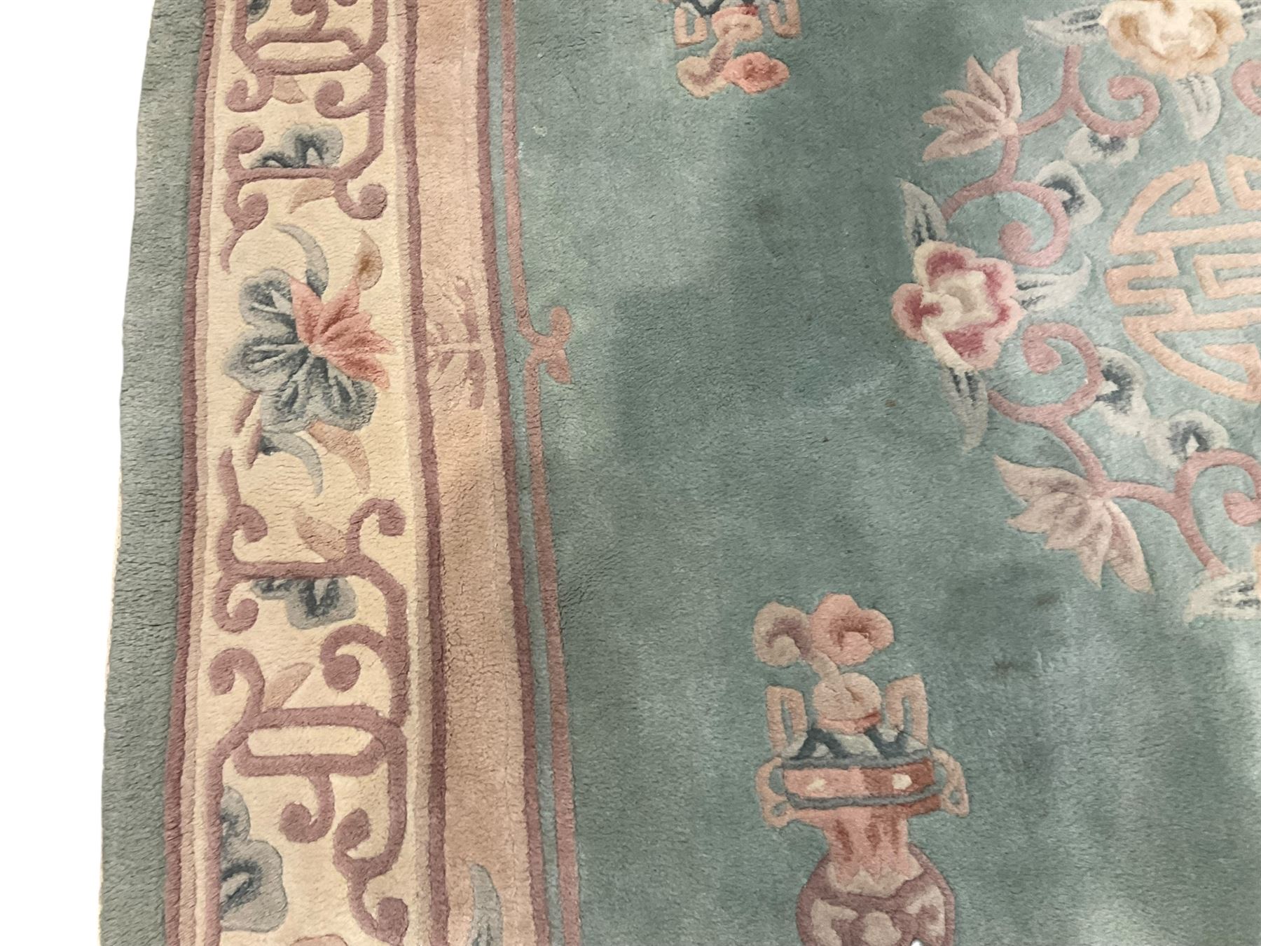 Chinese pale turquoise ground washed woolen rug, oval form decorated with bouquets of floral designs and Chinese characters, enclosed by a wide guard band