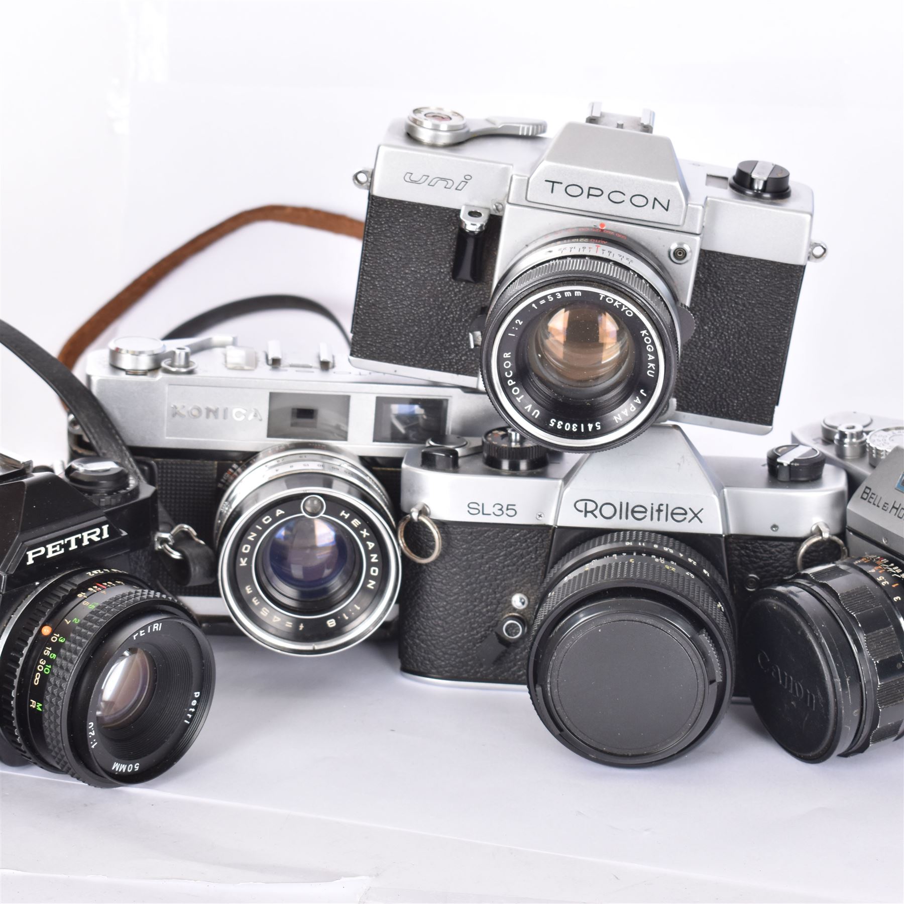 Five SLR cameras, to include Rolleiflex SL35, with a Rollei-HFT Planar 1.8/50 lens serial no. 1246774, Topcon Uni serial no. 5417650, with a Topcor Kogaku UV 1:2 f=53mm lens serial no. 5413035, Bell & Howell Auto35/Reflex Design 237, with a Canon EX 50mm 1:1.8 lens serial no. 92960, Petri GX-1 serial no. 91206945, with a Petri 50mm 1:2.0 lens serial no. 91107428, and a Konica Auto 52 serial no. 1193641, with a Konica Hexanon 1:1.8 f=45mm lens, all in cases 