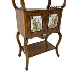 Mid-to-late 20th century French figured walnut three-tier bedside stand, shaped moulded top inlaid with figured book-matched veneers and crossbanding, double cupboard below enclosed by two doors mounted by painted porcelain panels depicting courting scenes within landscapes, on cabriole supports united by undertier, decorated with ornate cast metal cartouche mounts 