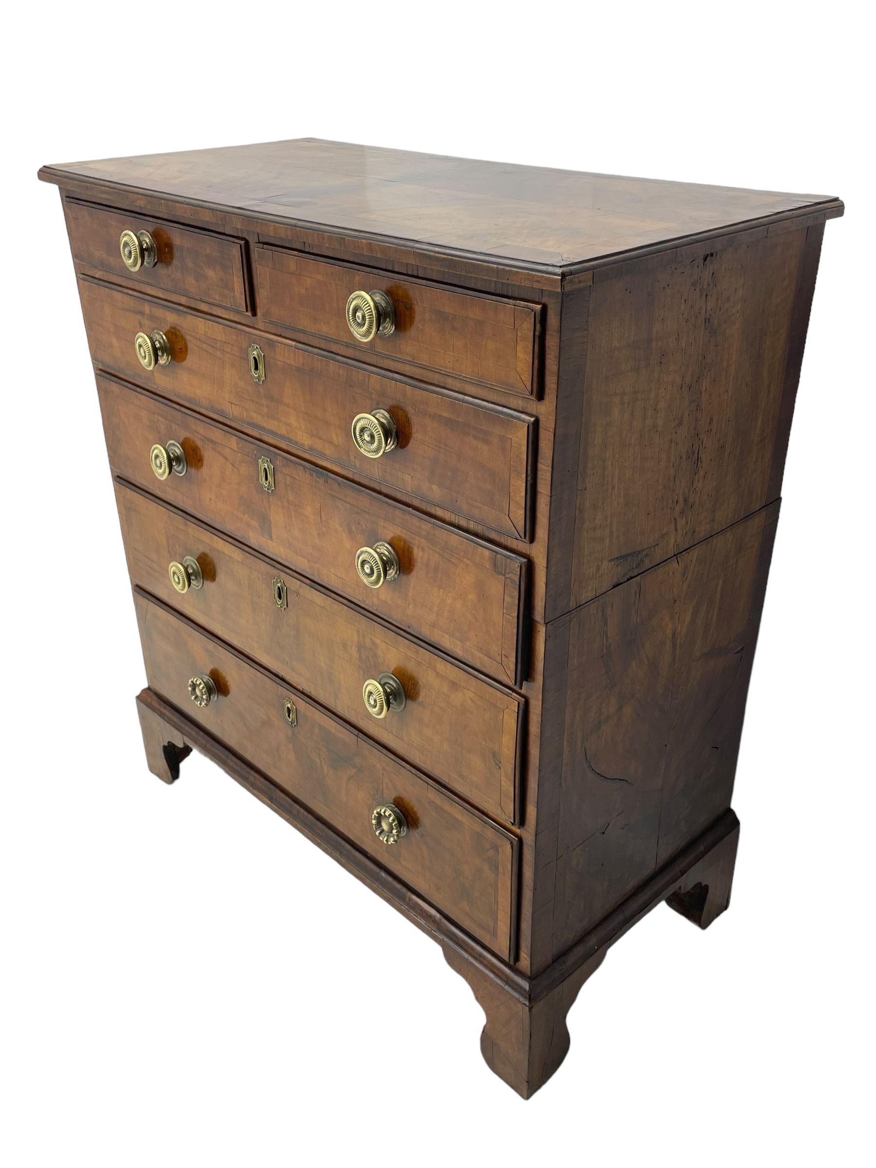 George I walnut chest, moulded rectangular top with book-matched veneers within crossbanding, fitted with two short over four long graduating drawers, moulded drawer fronts with brass handles, on bracket feet, the chest will split into two sections 