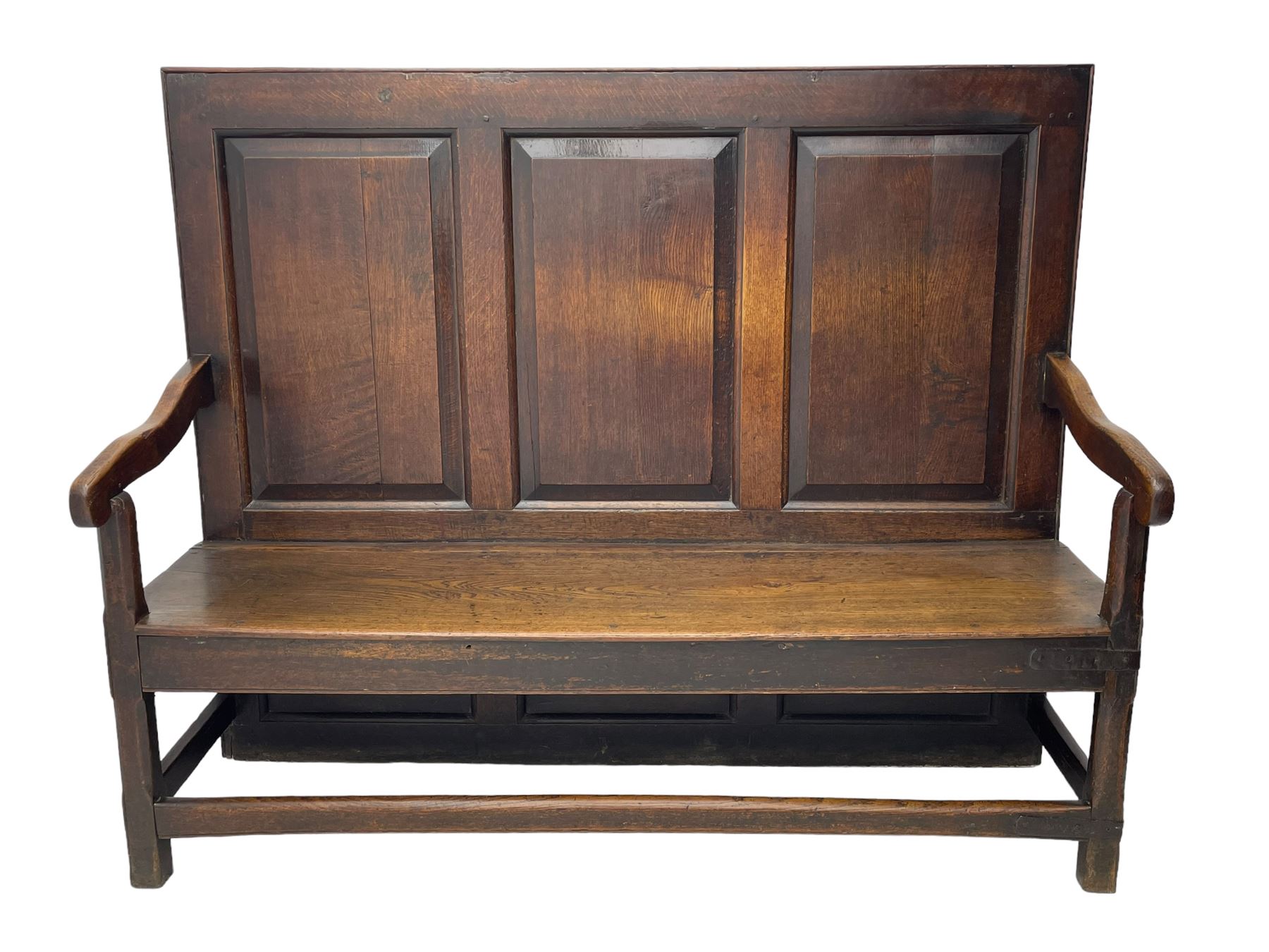 18th century oak settle, the high back with three fielded panels, shaped arms and solid plank seat, standing on square supports joined by stretchers