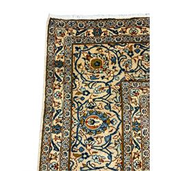 Persian Kashan golden ivory ground carpet, the central medallion surrounded by a field of interlacing branch and stylised plant motifs, the guarded border with scrolling design decorated with flower heads 