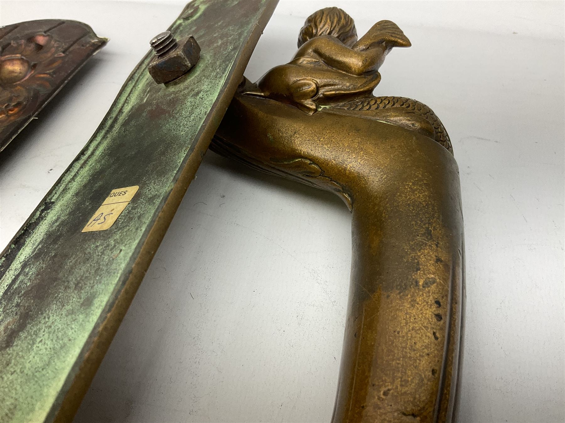 Art Nouveau bronze door handle modelled with a young merman holding a stylised fish, the plate decorated with geometric terminals, together with three repousse detail finger plates, largest L36cm