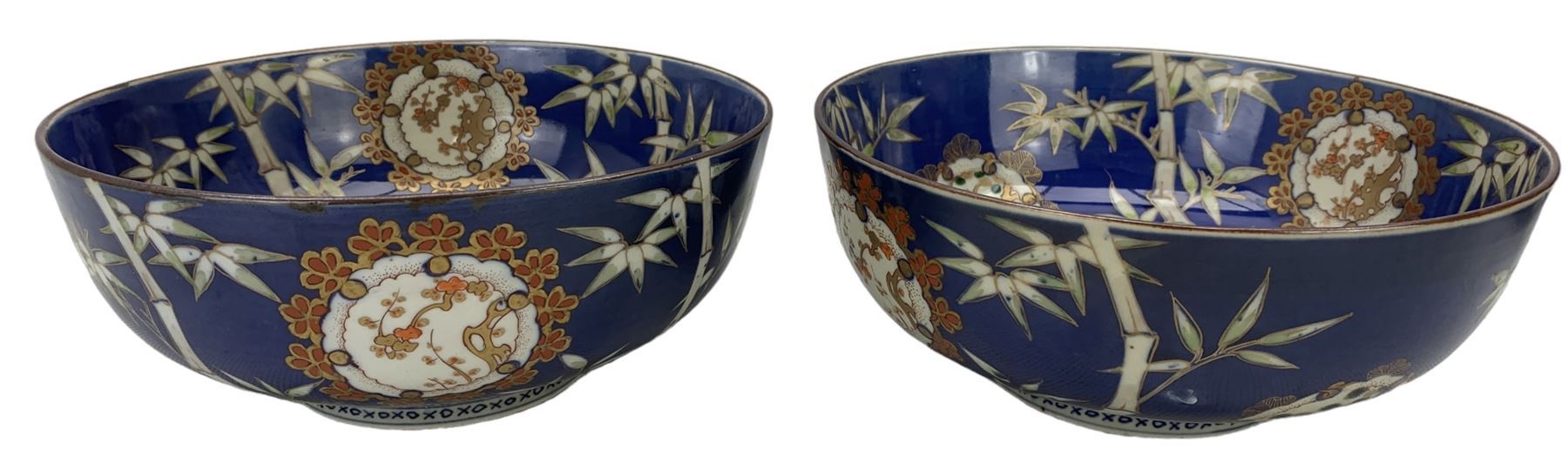 Set of four Japanese graduating porcelain bowls, each centrally painted with a coiled dragon in reserves, bamboo and foliate roundels against a blue ground, largest measuring D24.5cm (4)