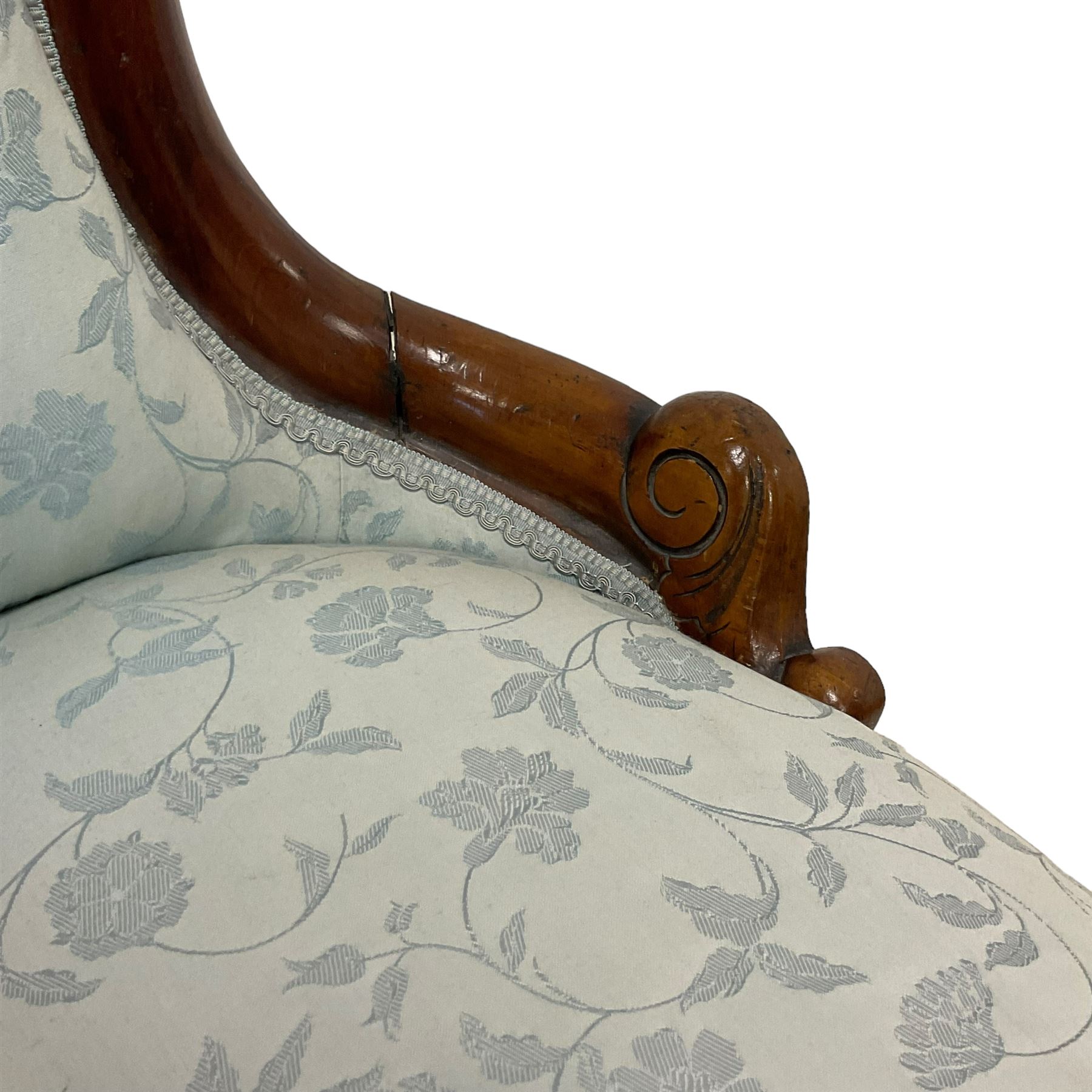 Victorian walnut nursing chair, the curved cresting rail carved with central cartouche and scroll leaves, upholstered in pale blue fabric decorated with trailing floral design, on cabriole front feet 