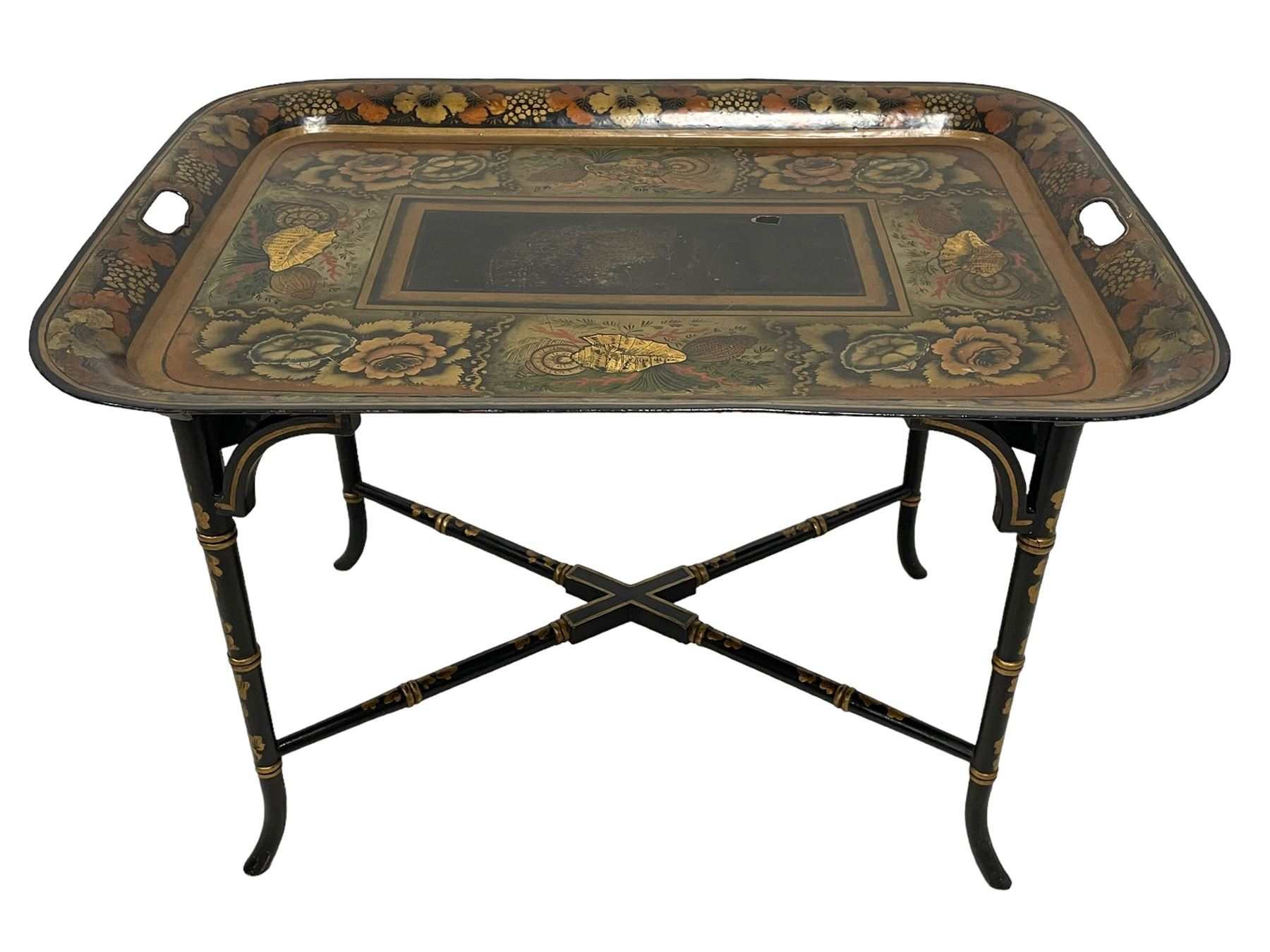 19th century tole ware tray of rectangular form, decorated with Japanese inspired floral motifs and gilt shells, with pierced handles, the associated ebonised and gilt stand, raised on ring turned splayed supports united by X-stretcher, decorated with gilt foliage